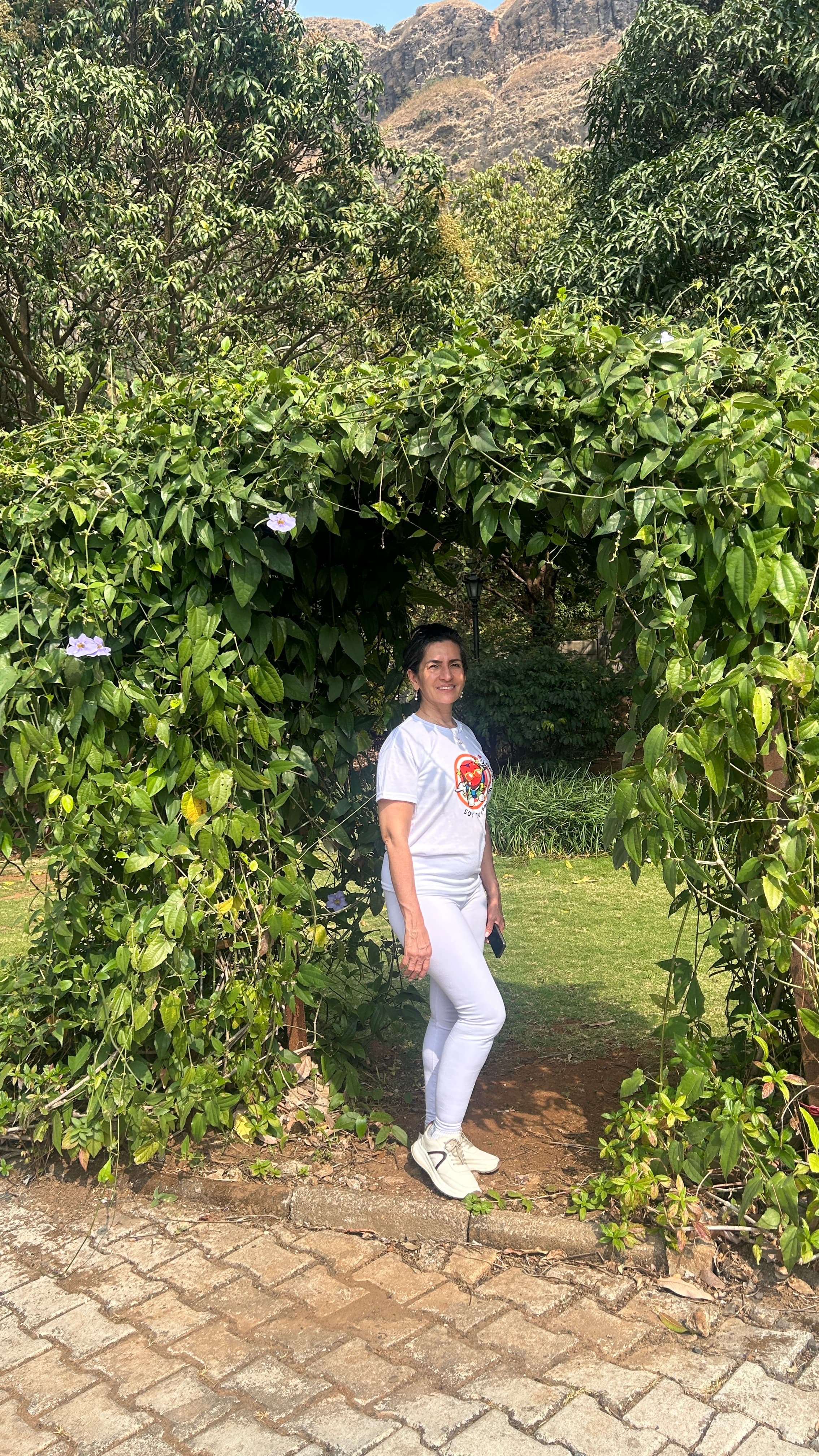 Dra. Diana Cuervo en los jardines del retiro en India, con las montañas al fondo